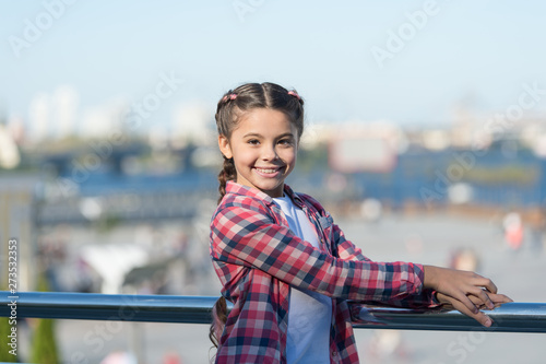 She is really cute. Little child with brunette hair smiling in casual fashion style. Adorable child on summer day. Happy girl child on city street. Small child with charming smile and beauty look
