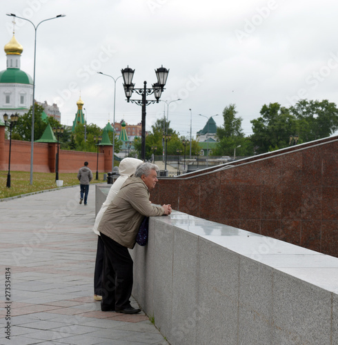 an elderly man and woman standing on the street in the city talking and laughing on a summer day