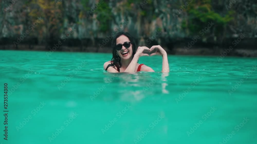 girl shows heart sign in water