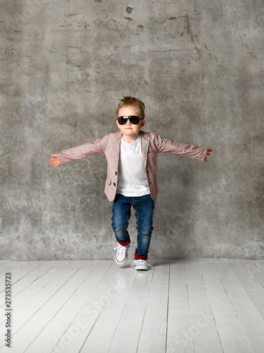 Image of cheerful excited little boy child standing isolated over concrete wall.