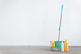 Bucket with a mop and bottle of detergent on a floor on a white wall background with copy space. Wet cleaning concept background.