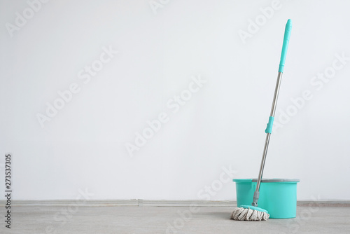 Bucket with a mop on a floor on a white wall background with copy space. Wet cleaning concept background. photo