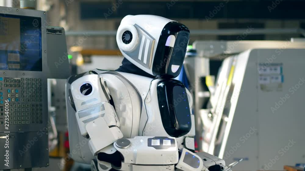 Human-like droid is operating a tablet in a factory unit Human-like droid is operating a tablet in a factory unit