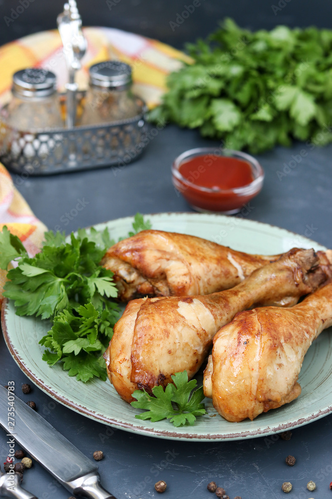 Chicken drumsticks, baked in a marinade of ketchup, soy sauce and balsamic vinegar on a plate on a dark background Chicken drumsticks, baked in a marinade of ketchup, soy sauce and balsamic vinegar on a plate on a dark background