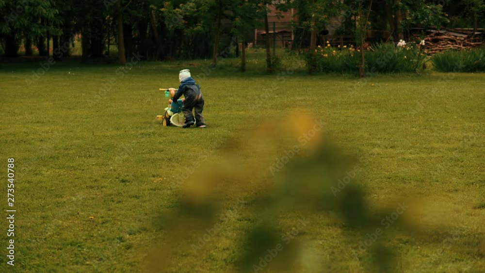 Little baby boy pushing bicycle playing at meadow forest park playground kid child enjoying walking Little baby boy pushing bicycle playing at meadow forest park playground kid child enjoying walking