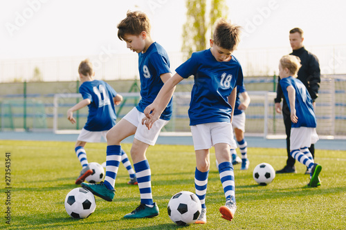 Children Training Soccer on Field. Young Kids Boys kicking Soccer Football Balls on Grass Pitch. Kids in Sportswear Practice Soccer Skills © matimix