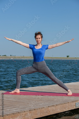 Pretty woman practicing yoga at a lake