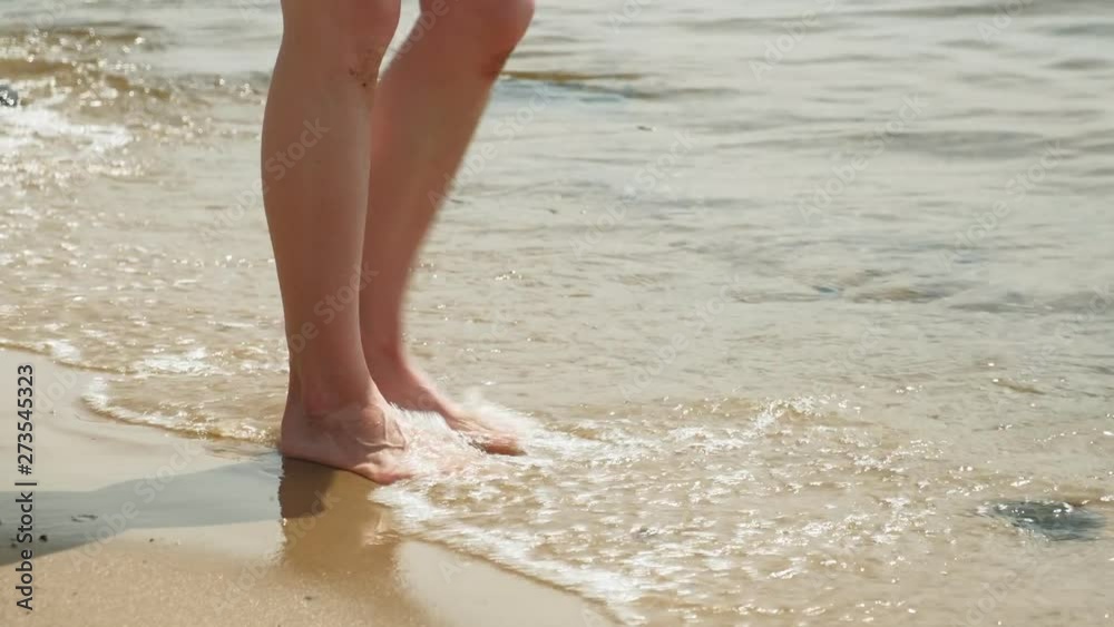 Feet are on the sand near the water. Beach. Summer sunny day Feet are on the sand near the water. Beach. Summer sunny day