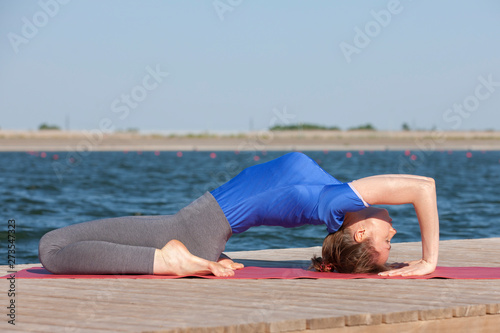 beautiful caucasian woman exercising yoga in nature next to a lake