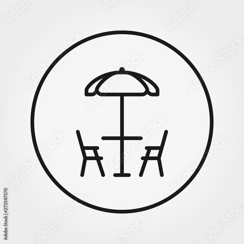 Table and chairs under umbrella. Beach cafe.