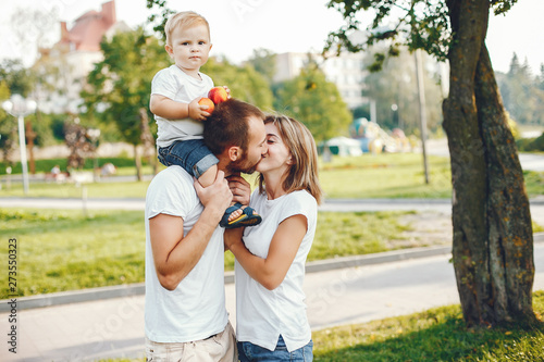 Family in a summer park. Mother in a white t-shirt. Cute little boy with a dad © hetmanstock2