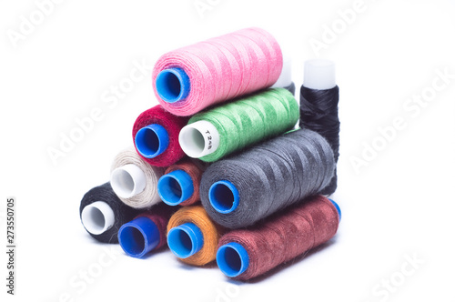 Spools of thread laid horizontally on top of each other on white background