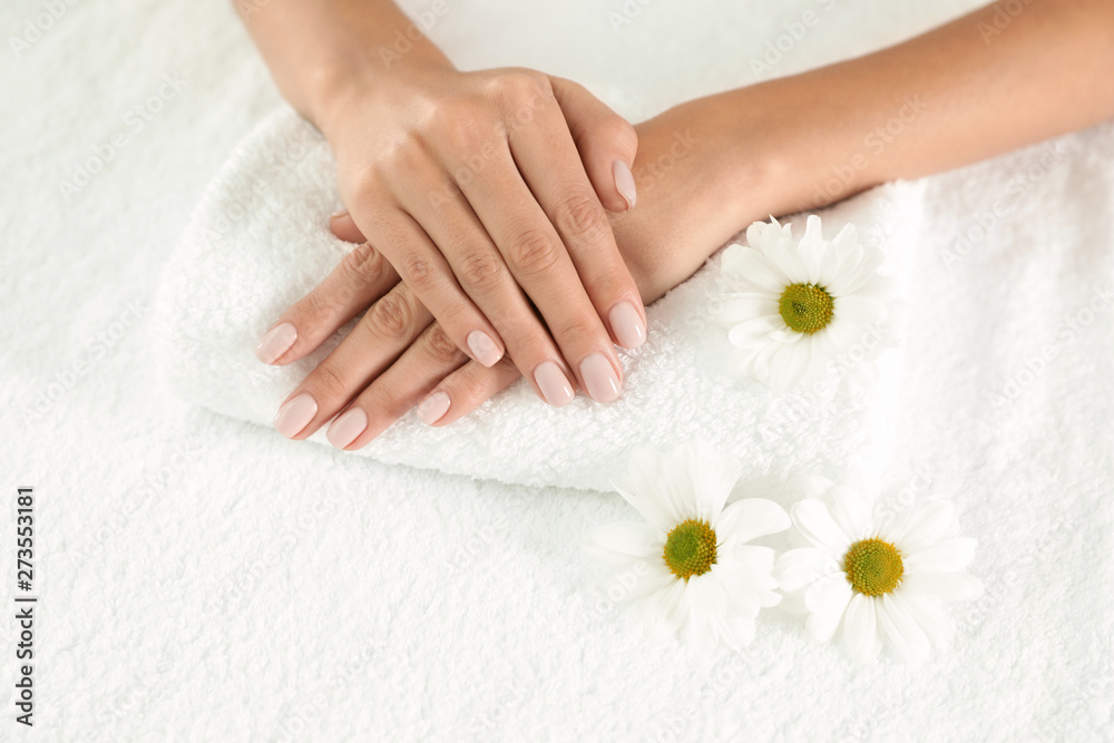 Woman with smooth hands and flowers on towel, closeup. Spa treatment