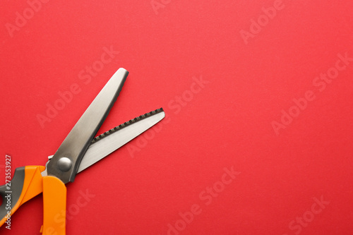 Pair of sharp scissors on color background, top view. Space for text