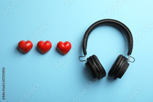 Decorative hearts and modern headphones on color background, flat lay