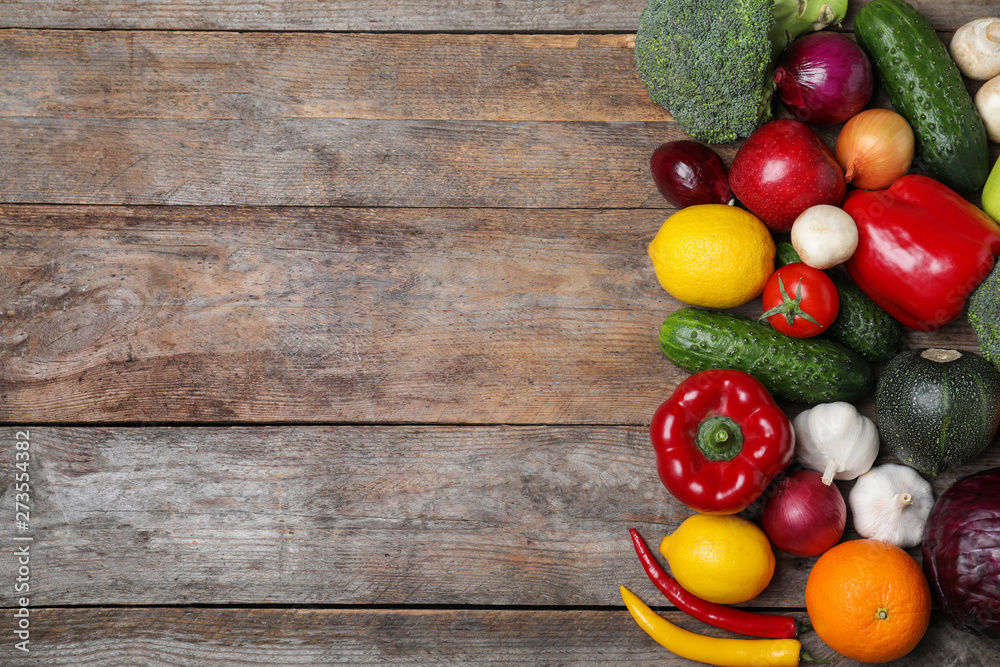 Variety of fresh delicious vegetables and fruits on wooden table, flat lay. Space for text Variety of fresh delicious vegetables and fruits on wooden table, flat lay. Space for text