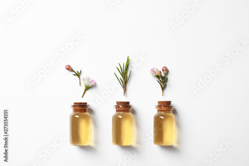 Flat lay composition with bottles of natural tea tree oil on white background