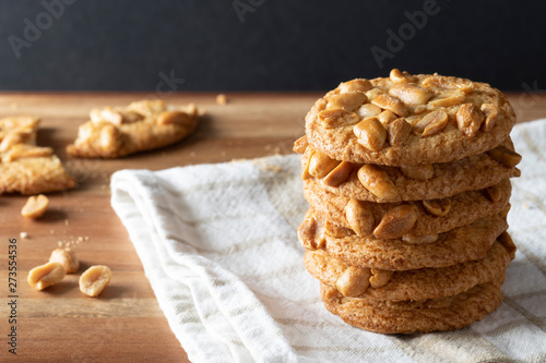 A stack of crisp peanut biscuits with a broken biscuit in the bakground. photo