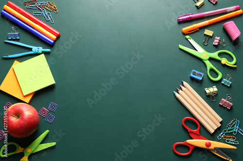Flat lay composition with scissors and school supplies on chalkboard. Space for text