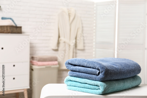 Clean folded towels on table in bathroom. Space for text