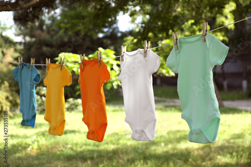 Colorful baby onesies hanging on clothes line outside