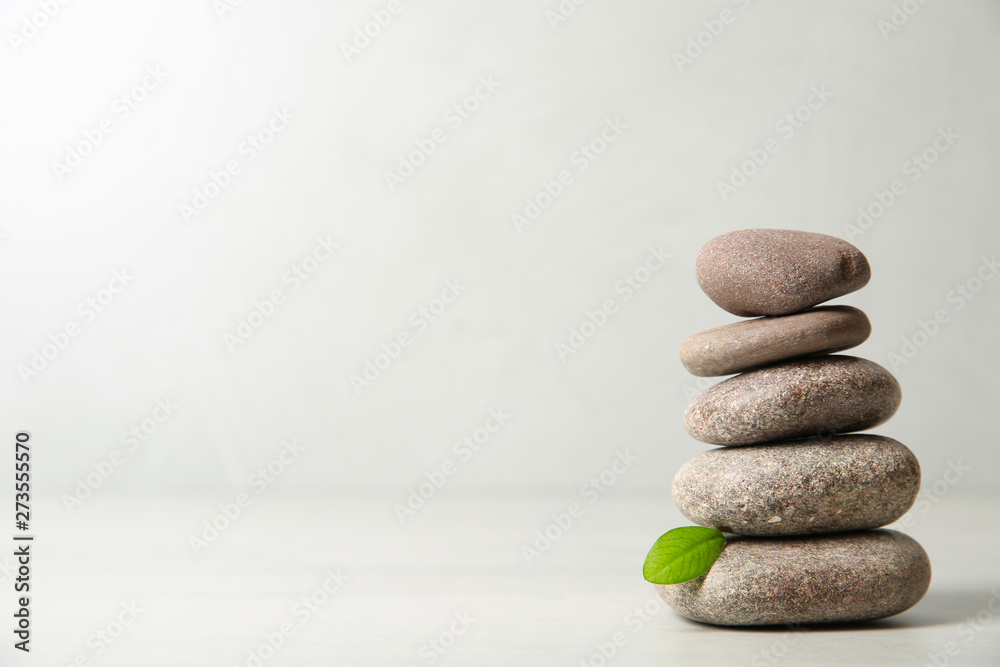 Stack of spa stones with leaf on light background. Space for text - obrazy, fototapety, plakaty 