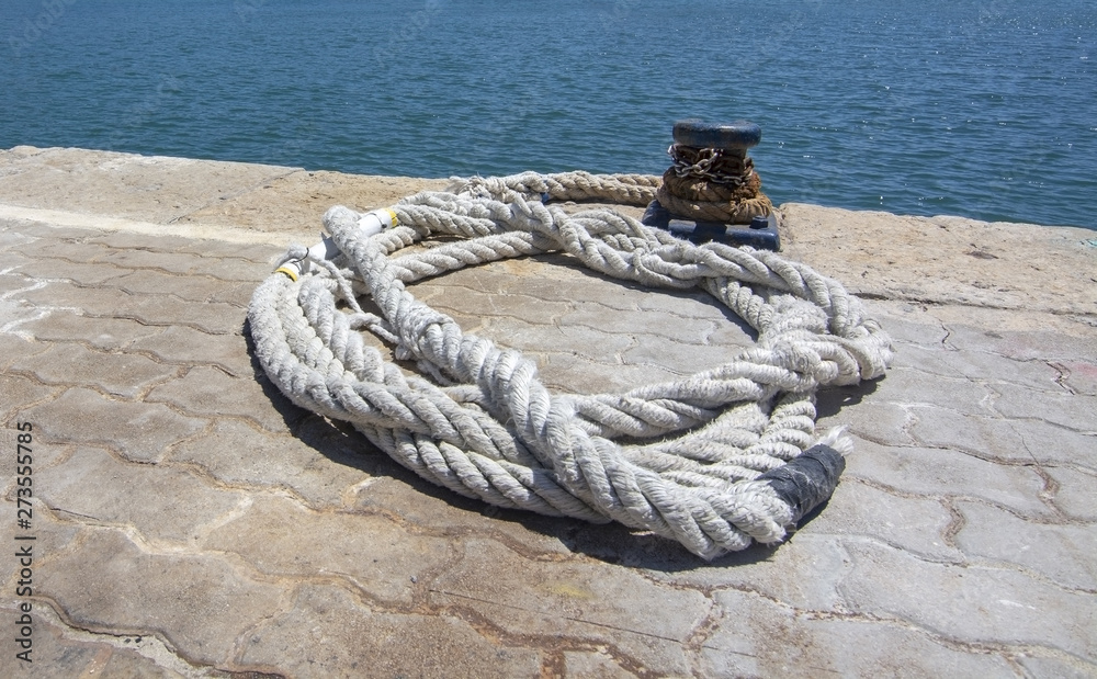 Thick white mooring rope closeup on empty mooring place