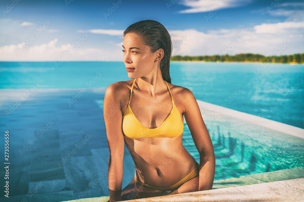 Sexy Asian bikini model woman sun tanning in infinity pool at luxury hotel in Bora bora , Tahiti, French Polynesia. Swimsuit body summer vacation travel tan.