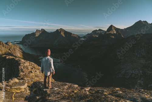 Man mountaineer standing on rock of peak mountain at sunset. Ryten Mountain, Norway