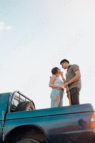 Beautiful Young couple kissing on top of jeep 4x4 car on sunset