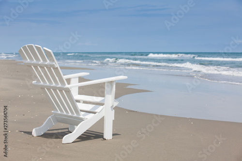 Empty white wooden chair at a paradisiac beach on the tropics in a beautiful sunny day