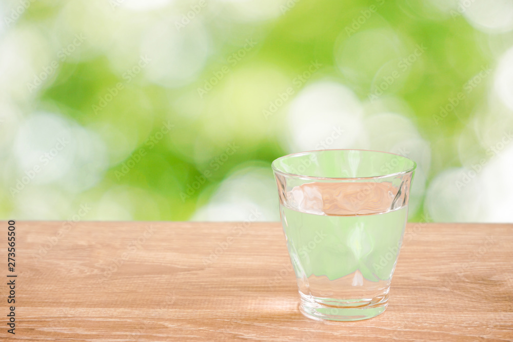 Glass of water on the table. Nature background. テーブルの上にあるグラス一杯の水と自然背景 Glass of water on the table. Nature background. テーブルの上にあるグラス一杯の水と自然背景