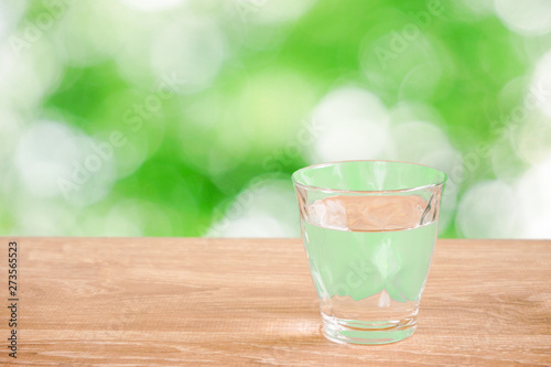 Glass of water on the table. Nature background. テーブルの上にあるグラス一杯の水と自然背景