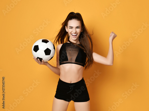 Sporty woman player or fan in black uniform with the soccer ball celebrates happily a win © Dmitry Lobanov