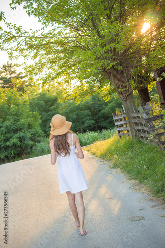 Cute young girl in white dress with yellow summer hat walking. Vacation concept © stivog