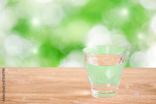 Glass of water on the table. Nature background. Backlight addition version. テーブルの上にあるグラス一杯の水と自然背景。逆光追加版