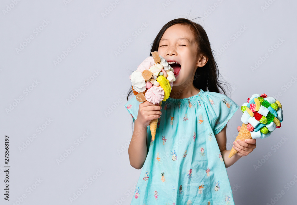 Baby girl kid eating two sweet big ice-cream in waffles cones with tasty raspberry marshmallow marmalade Baby girl kid eating two sweet big ice-cream in waffles cones with tasty raspberry marshmallow marmalade