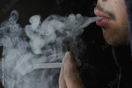 Man smoking cigarette on a black background, Anti drug concept.