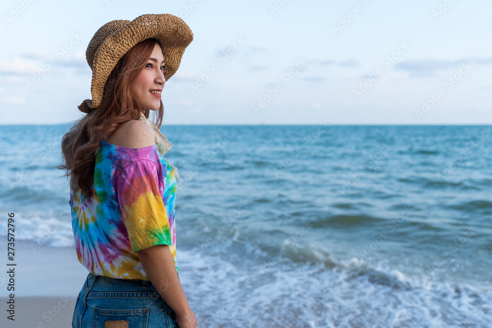 woman wearing hat standing on sea beach