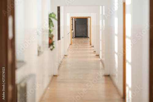 Long empty hallway inside an old building with white freshly painted walls and parquet floors