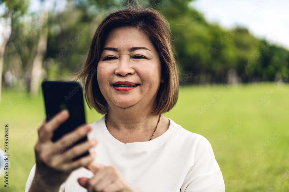 Portrait of happy senior adult elderly asia women smiling and using and talking on the phone in the park.Retirement concept Portrait of happy senior adult elderly asia women smiling and using and talking on the phone in the park.Retirement concept