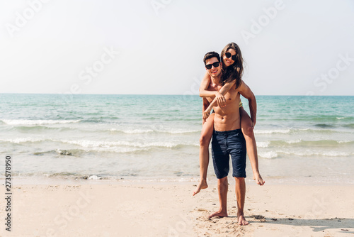Romantic lovers young couple relaxing together on the tropical beach.Man carrying a girl on his back.Summer vacations © Art_Photo
