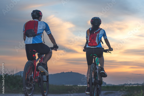 couple lover biker cyclist riding enjoyment to the field of meadow lake at sunset  adventure bicycle wild and journey activity