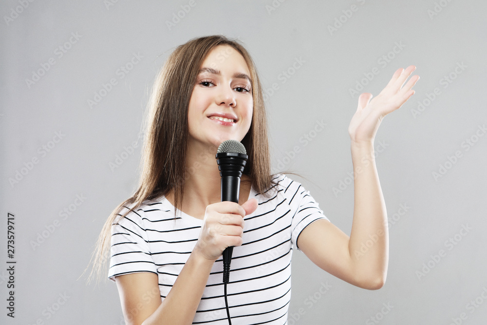 Beauty model girl singer with a microphone over light grey background Beauty model girl singer with a microphone over light grey background