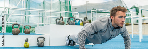 Pushup fitness man exercising in outdoor gym doing workout push up banner panorama. Young healthy male athlete.