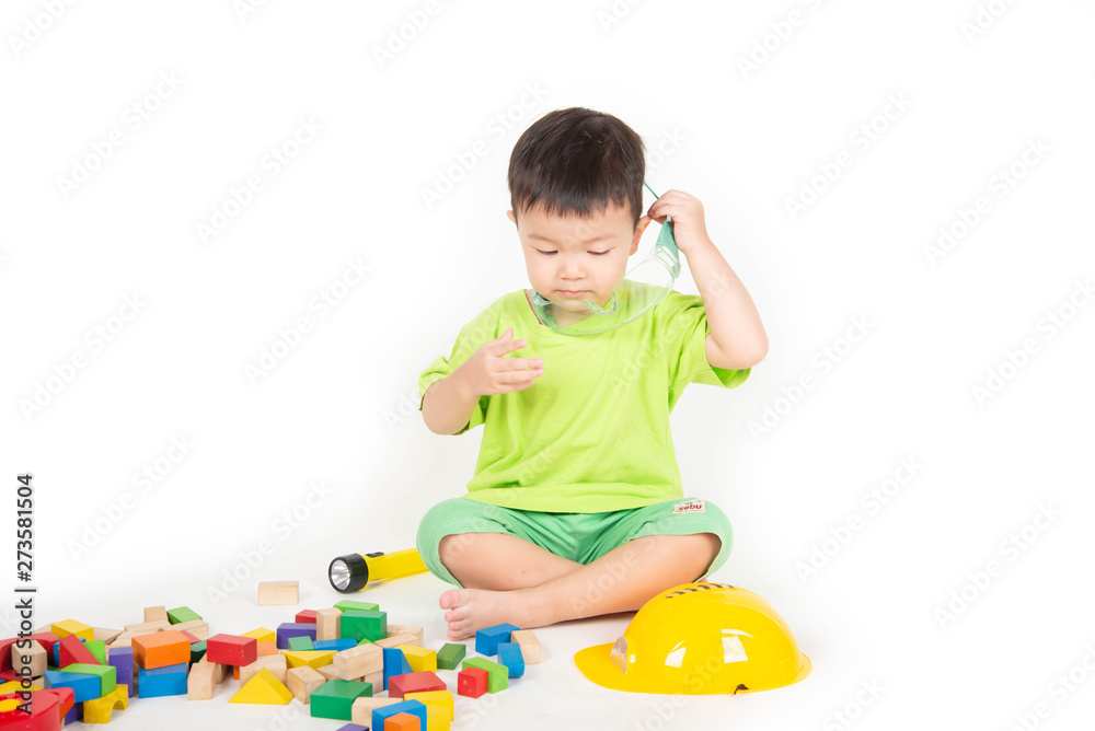 Little Asian toddler boy playing wood blocks wear helmet engineer Little Asian toddler boy playing wood blocks wear helmet engineer