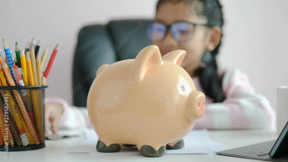 Little Asian girl puttinwg the coin into piggy bank and smile with happiness for money saving to wealthness in the future of education concept select focus shallow depth of field Little Asian girl puttinwg the coin into piggy bank and smile with happiness for money saving to wealthness in the future of education concept select focus shallow depth of field