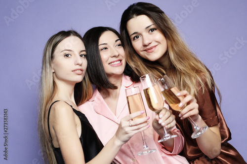Pajamas Party conept - beautiful girls dressed in pajamas drink champagne and have fun