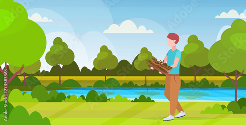 man hiker holding firewood for bonfire hiking camping concept traveler on hike beautiful nature landscape background full length horizontal flat