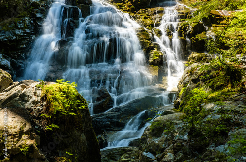 Fototapeta Naklejka Na Ścianę i Meble -  beautiful waterfall deep inside forest with sun illuminate the top and water running down the cascading creek on a hot summer day
